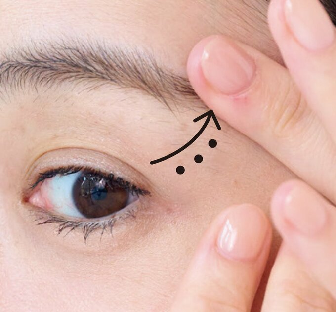 目尻を指先で優しく引き上げるようにクリームを塗る様子
