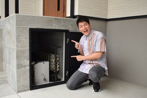 玄関の段差を利用した収納庫を指差すコジマジックさん