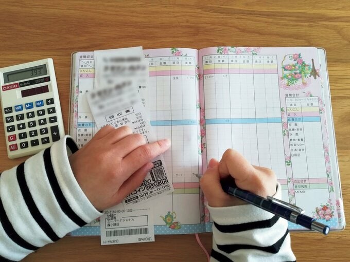 家計簿にレシートの内容を書き込む様子