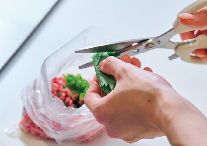 キッチンバサミで青ジソを刻んで袋に入れている様子