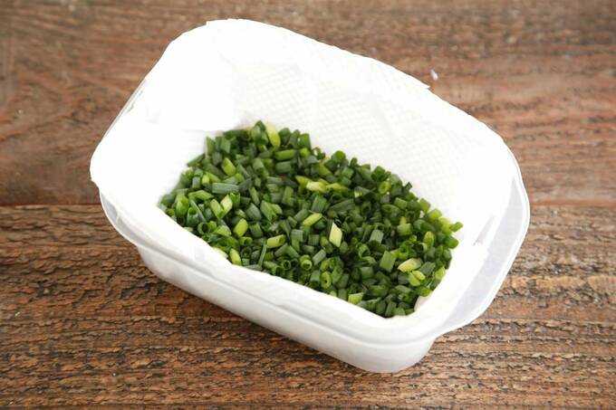 キッチンペーパーを敷いた保存容器に小口切りにした青ネギ