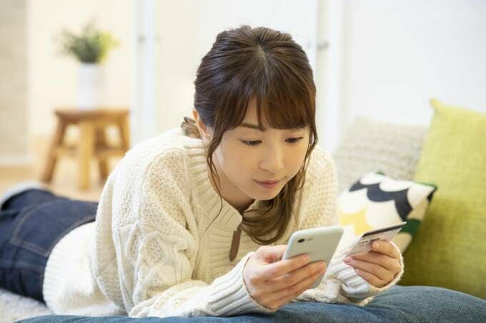 寝転んでスマホを見る女性