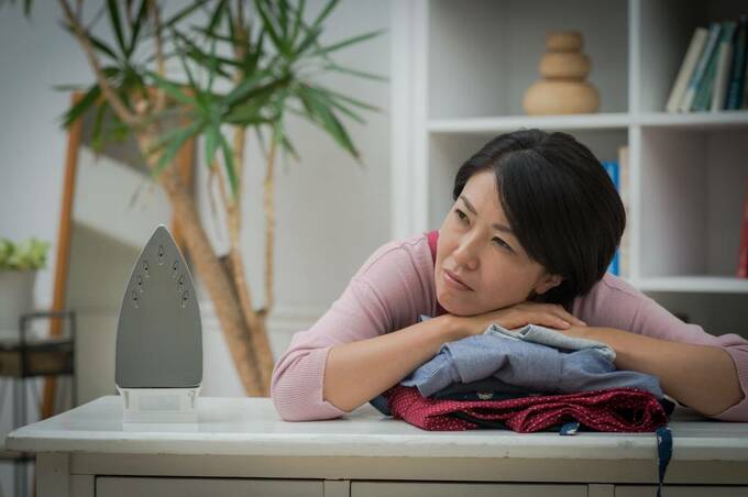 畳まれた服の上で悩む女性