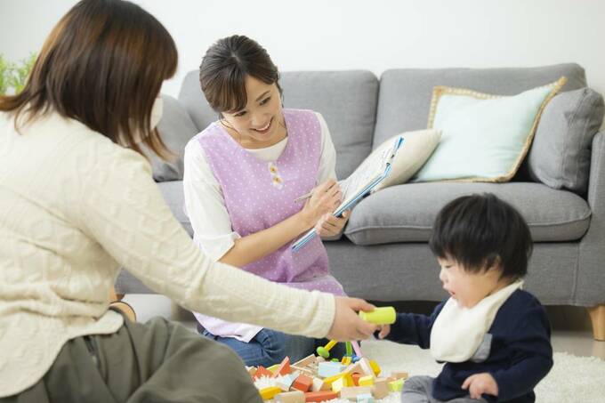オモチャで遊ぶ子どもとそれを見る女性