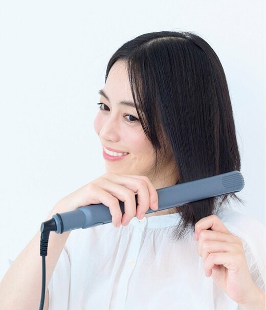 ヘアアイロンで髪を整える女性