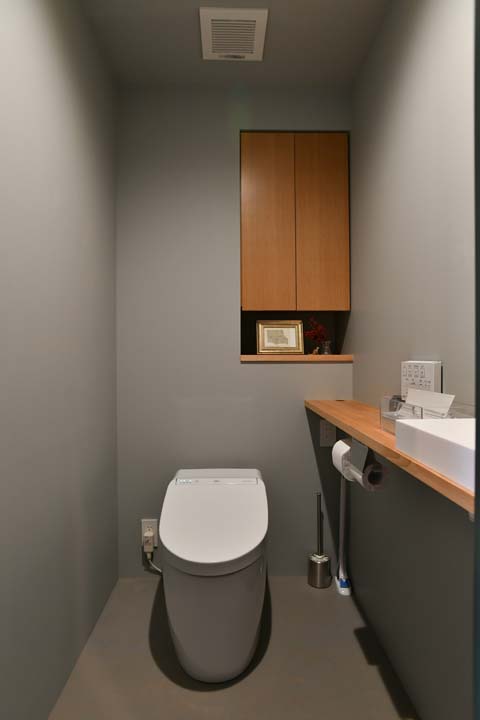 モルタルのようなシックな色合いのクロスで仕上げたトイレ