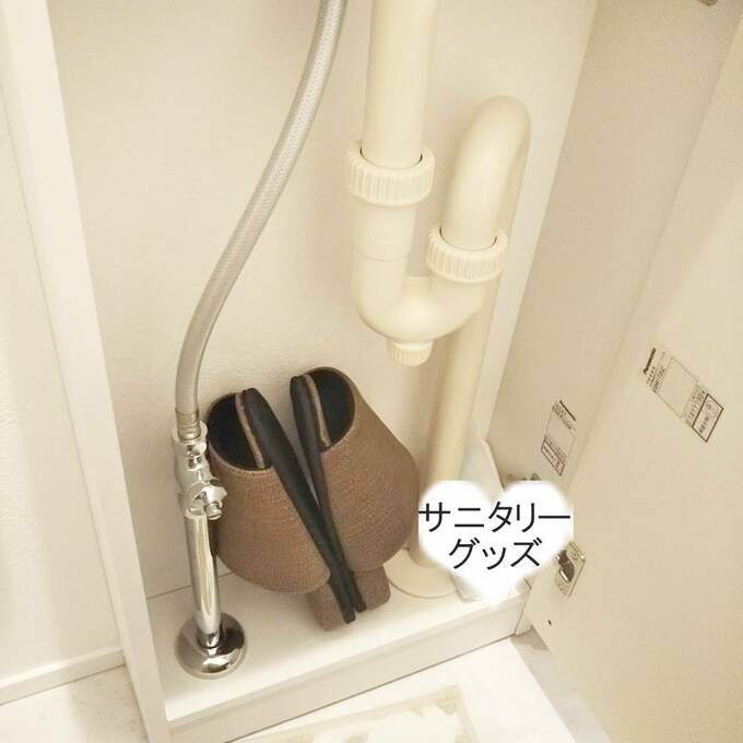 手洗い下の水道管が通っている小さなスペースには、来客用のスリッパとサニタリーグッズを置いています。