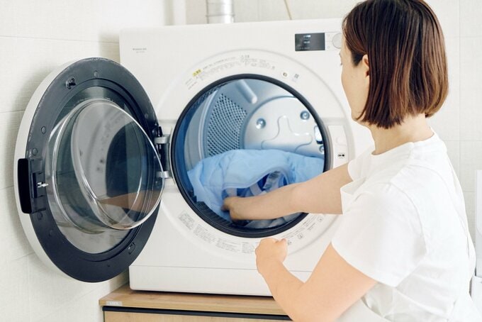 乾燥機に寝具を入れる女性