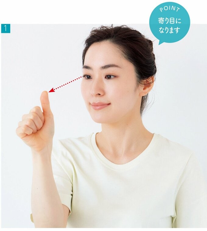 親指を立てて目から20cm程の距離で見つめる女性