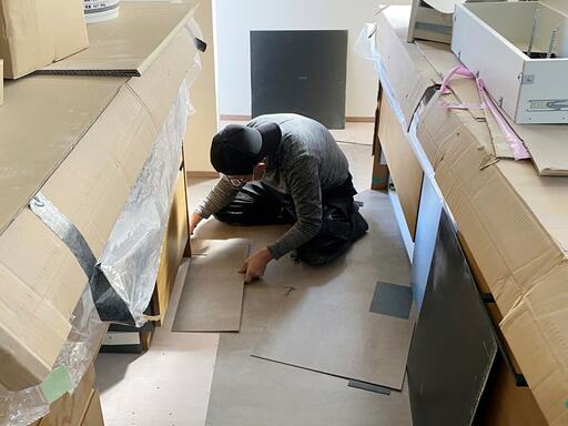 床にフロアタイルを貼り付け作業