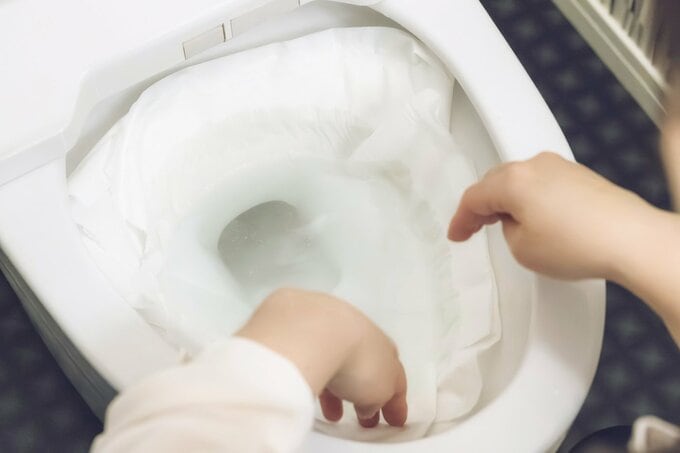 トイレットペーパーを便器の中に貼り付けている様子