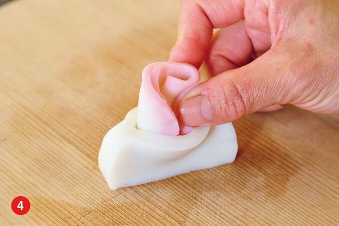 白かまぼこの切り目に紅かまぼこを差してバラ状に整える様子