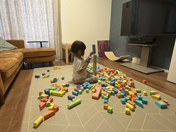 リビングのマットの上で娘が積み木を広げて遊んでいる