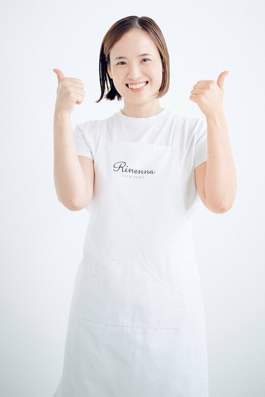 白Tシャツに白エプロンの女性が両親指を立てている様子