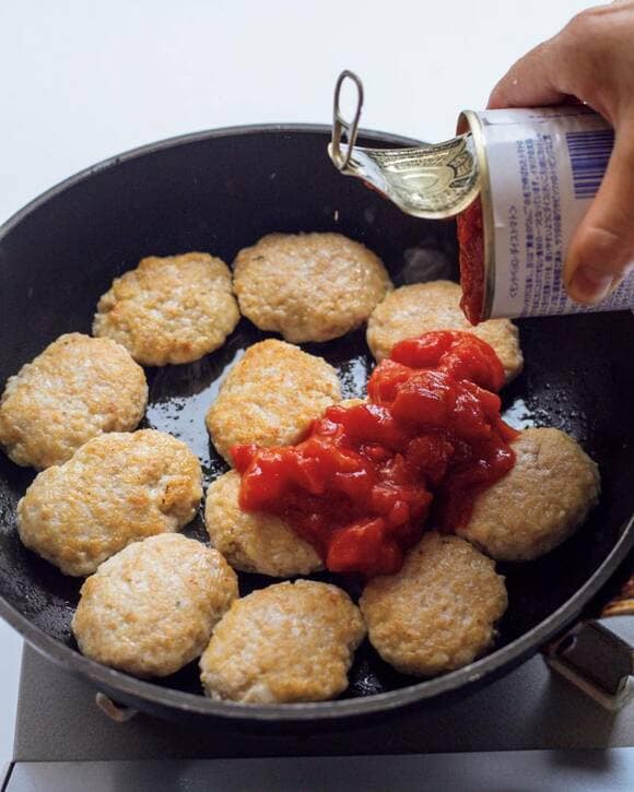 フライパンにトマト缶を入れる様子
