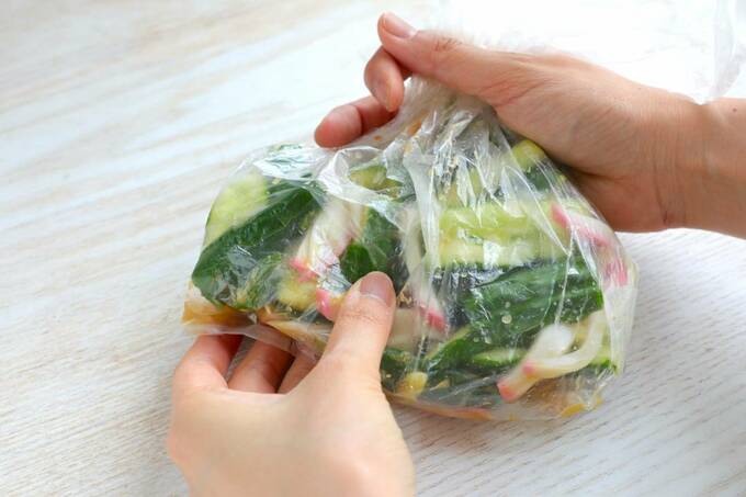 キュウリとかまぼこが入った袋をもむ