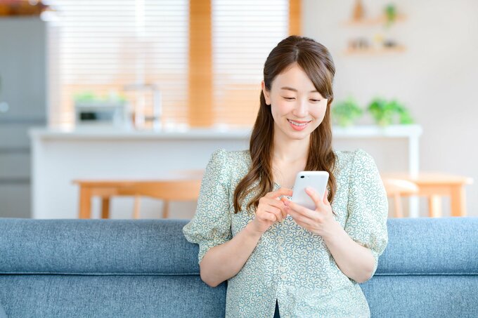 ソファでスマホを見る女性