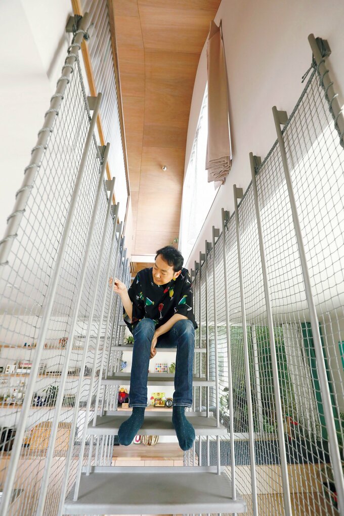 細身のスチール階段に座る田中さん
