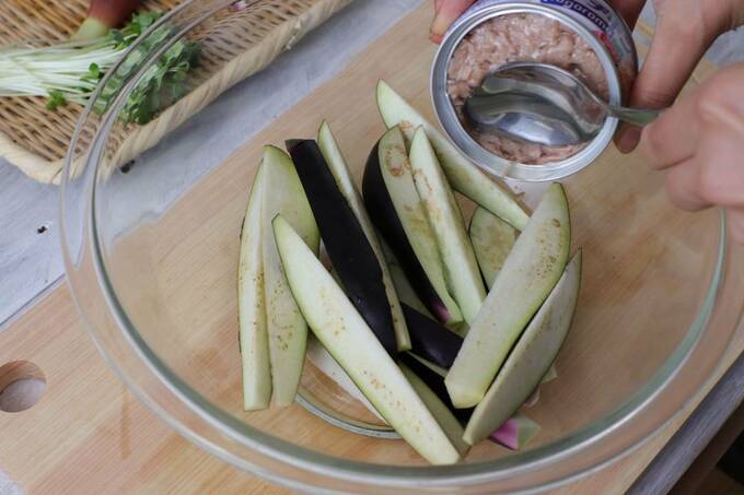 ナスが入った耐熱ボウルにツナの油を注ぐ様子