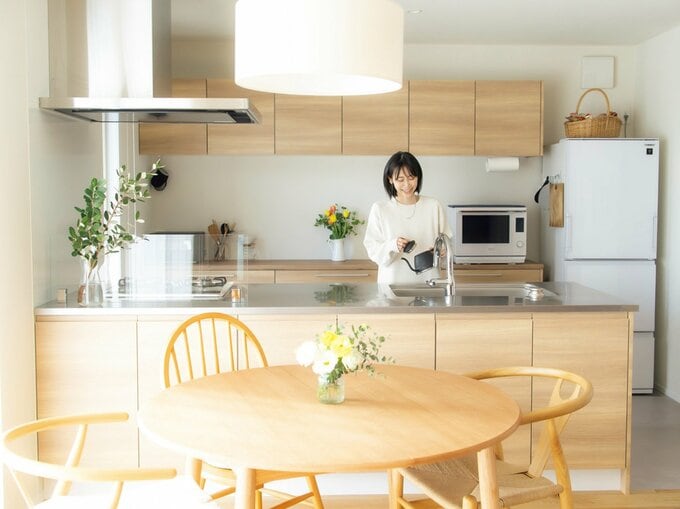 ケトルを手に持ってキッチンに立つ女性