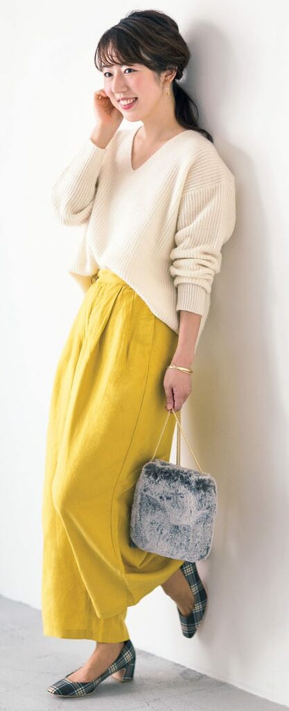 黄色のパンツはく女性壁にもたれる