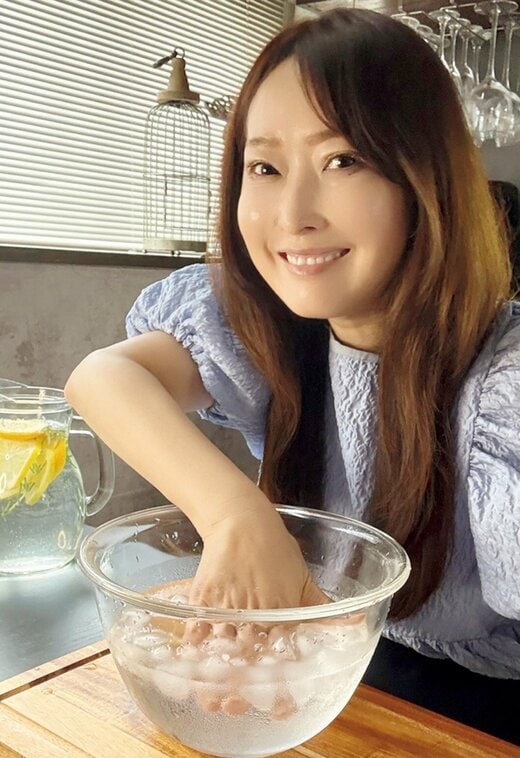 ガラスボウルに氷水を入れて手を冷やす女性