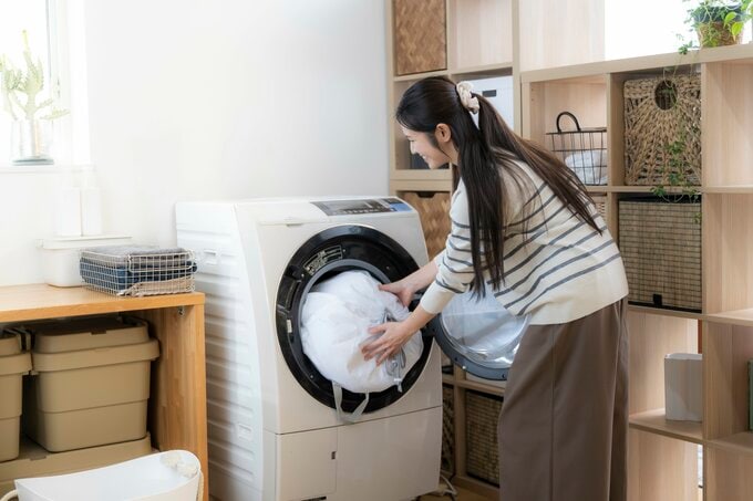 洗濯機に洗い物を入れる女性