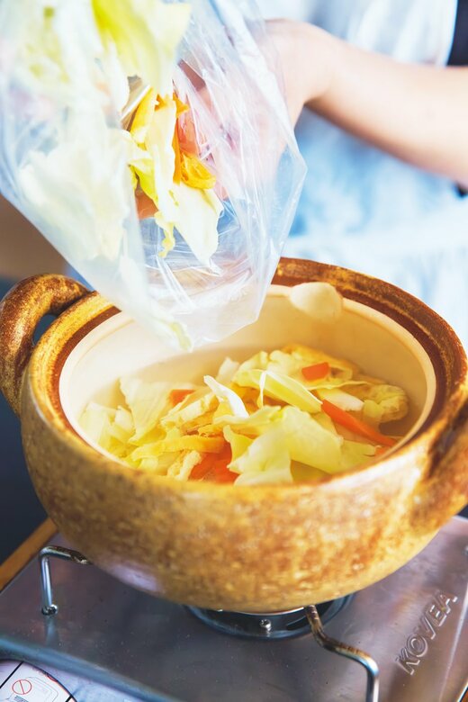 ポリ袋に入ったカット野菜を鍋に入れる様子