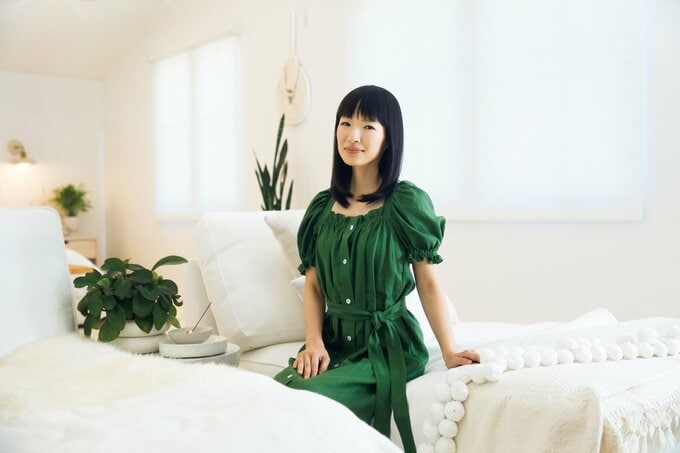 緑のワンピースを着た女性が白いソファに座っている様子