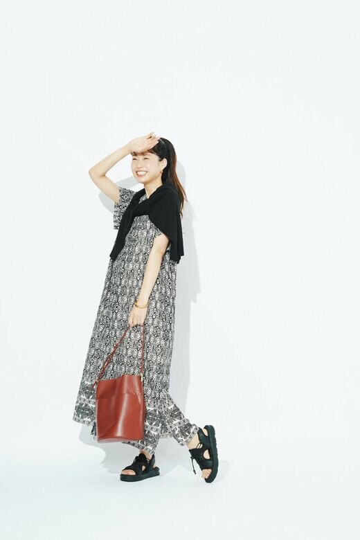 総柄のワンピースとブラックのレースアップサンダルを身に着けた女性