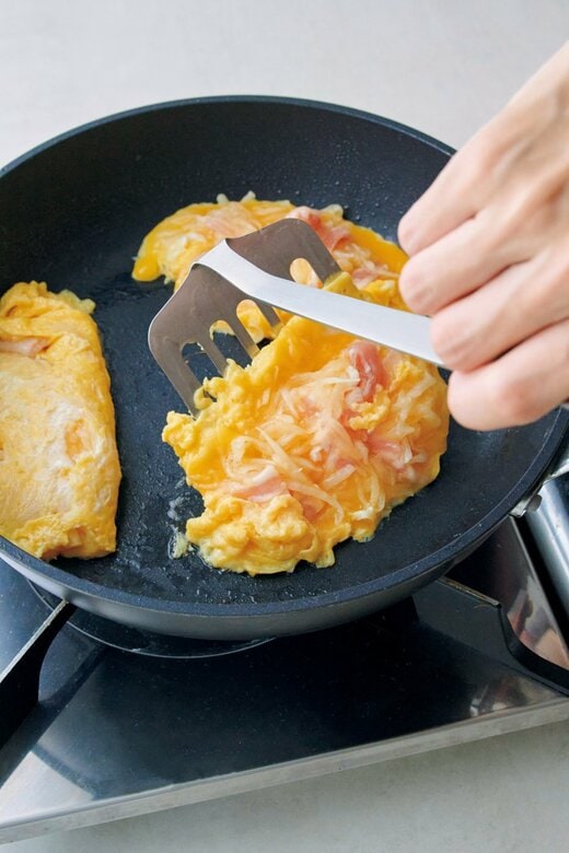 フライ返しで、大根の入った卵焼きを形成する様子