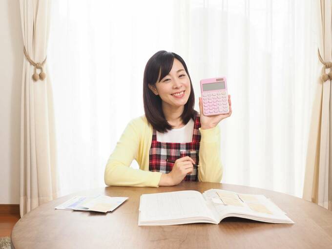 電卓をもって微笑んでいる女性の画像