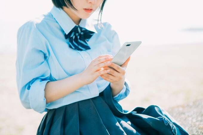 スマホを持つ制服の女性