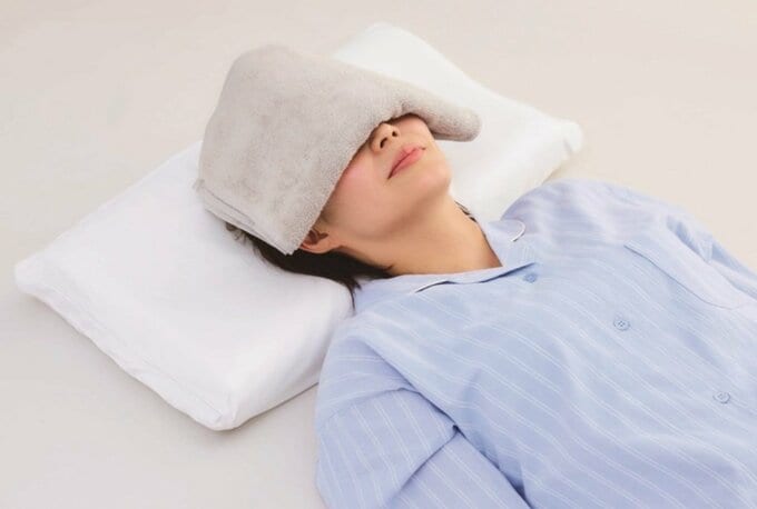 タオルを顔の上にのせて横たわる女性