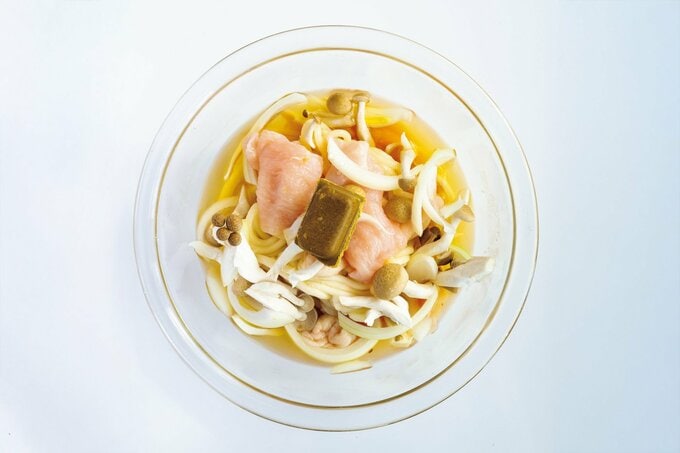 耐熱ボウルに入った鶏胸肉、カレールウ、うどん、野菜