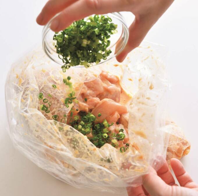 お肉が入ったポリ袋にネギを加える様子