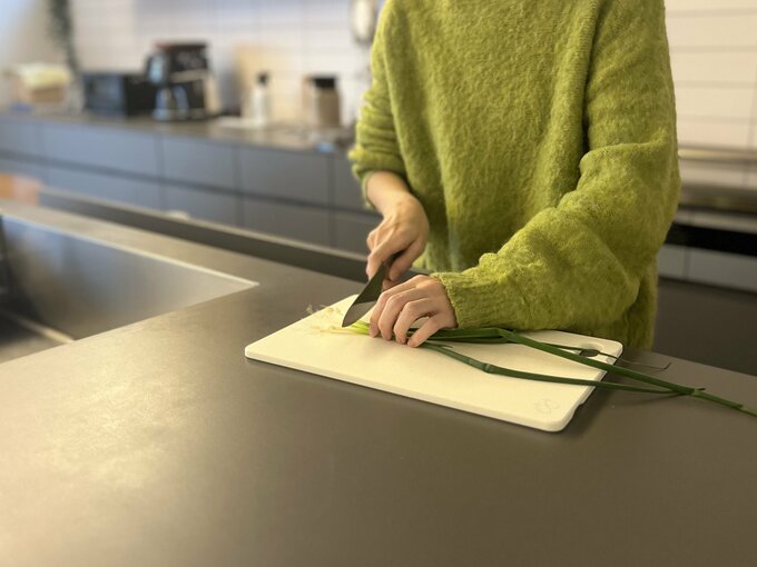 キッチンでネギを切る女性