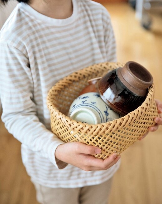 子どもがカゴにまとめた食器を運ぶ様子