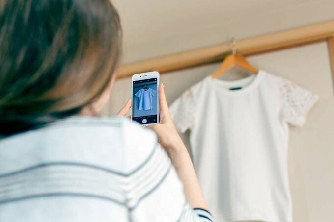 服をスマホで撮影する女性