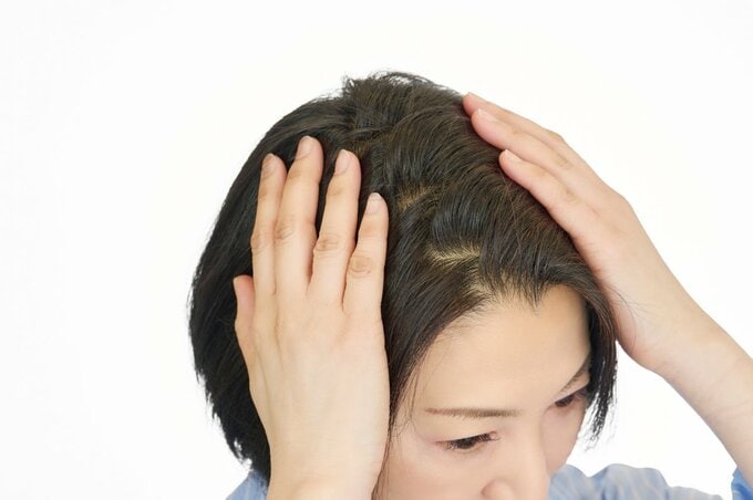 分け目を手でおさえる女性