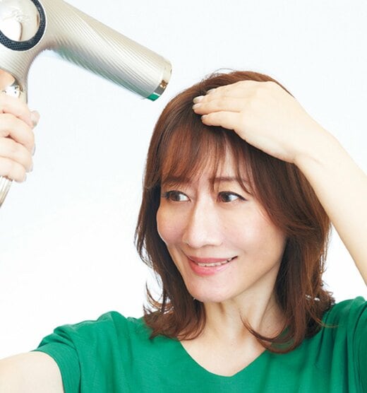 前髪の根元にドライヤーを当てる女性