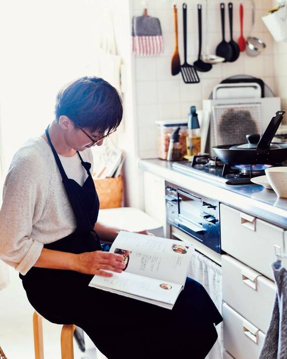 キッチンで読書をする女性