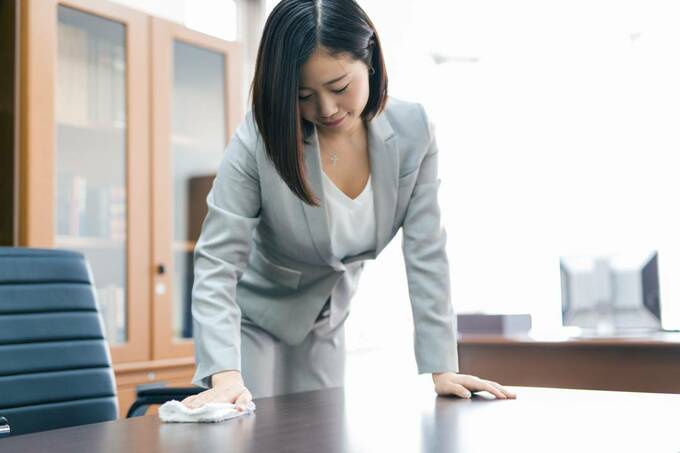 机をふくスーツの女性