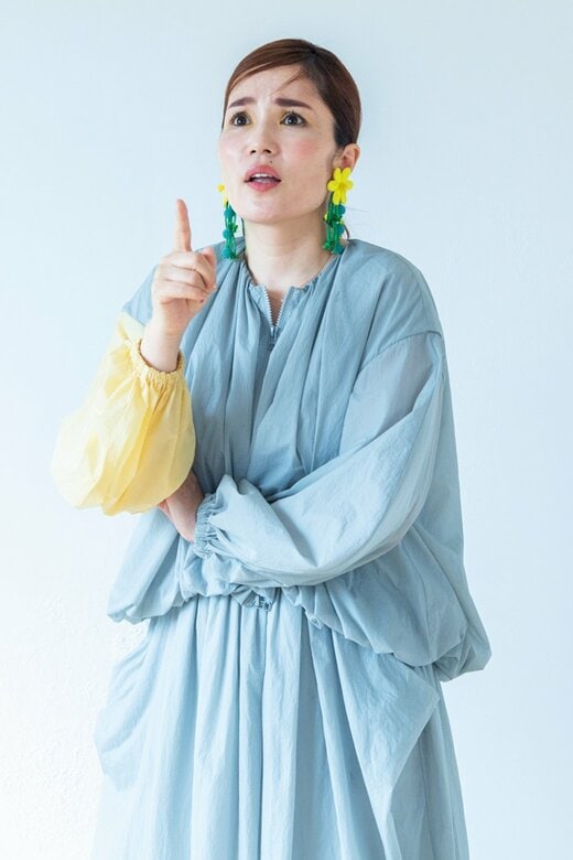 腕を組んで右手の人差し指を立て、斜め上を見上げる平野ノラさん