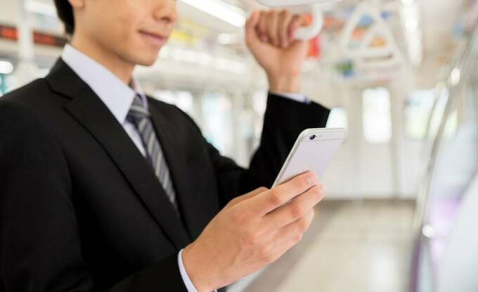 電車でスマホを操作する男性
