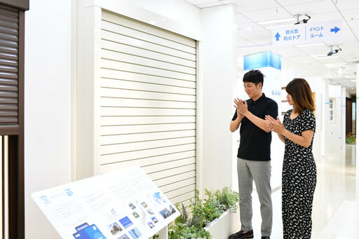 シャッターの前で拍手する2人