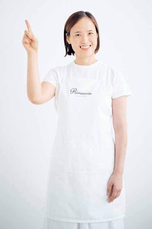 白のTシャツに白エプロンの女性が指さす様子