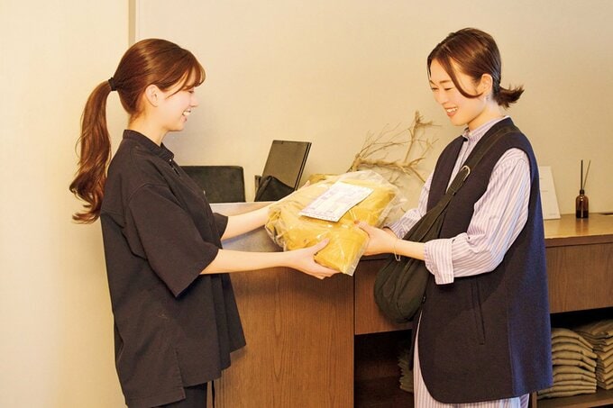 荷物をスタッフに手渡す女性