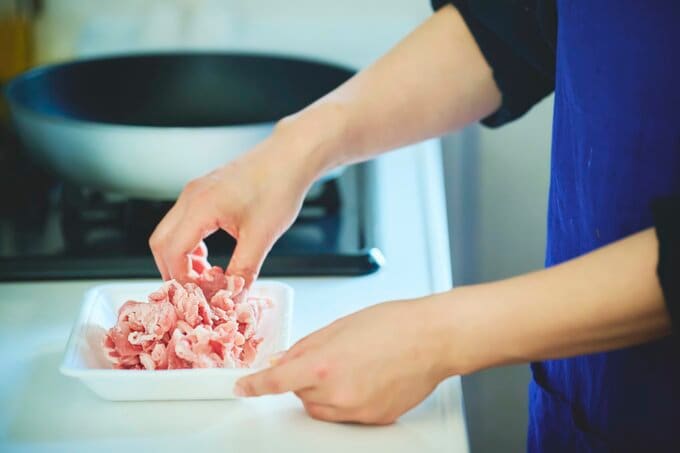 食品トレーに入った豚肉に片栗粉をまぶす図