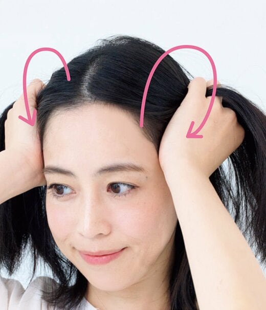 両手で髪を持ち上げながら頭皮マッサージする女性